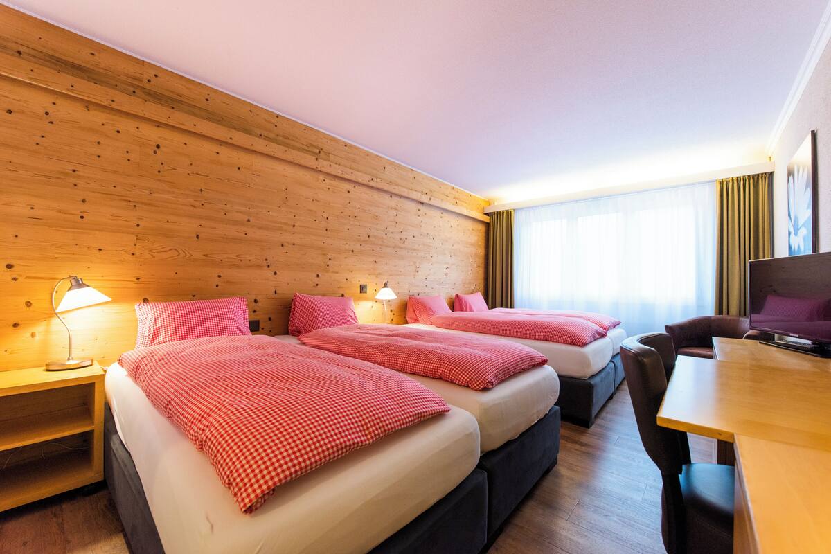 Ein Hotelzimmer mit zwei Betten, einem Schreibtisch und einem Fernseher.