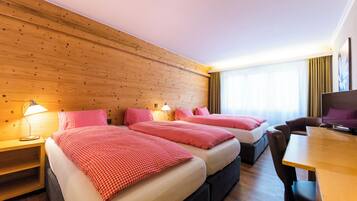 A hotel room with two beds, a desk, and a TV.