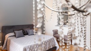 A bedroom with a large bed, a bedside table, a lamp, a chair, and a mirror. - BB 22 Charming Rooms & Apartments (Palermo)