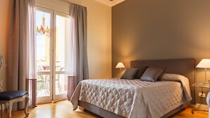 A bedroom with a bed, two bedside lamps, a chair, and a view through a glass door. - BB 22 Charming Rooms & Apartments (Palermo)