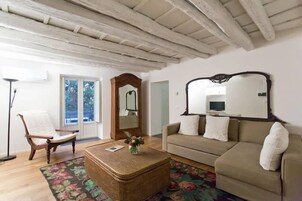 Una sala de estar con un sofá, un sillón, una mesa de centro y un espejo.