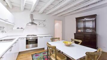 A modern kitchen with white cabinetry, stainless steel appliances, and a wooden dining table with chairs.