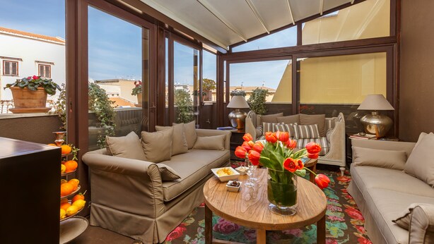 A sunlit living room with a sofa, armchairs, a coffee table, and a TV. - BB 22 Charming Rooms & Apartments (Palermo)