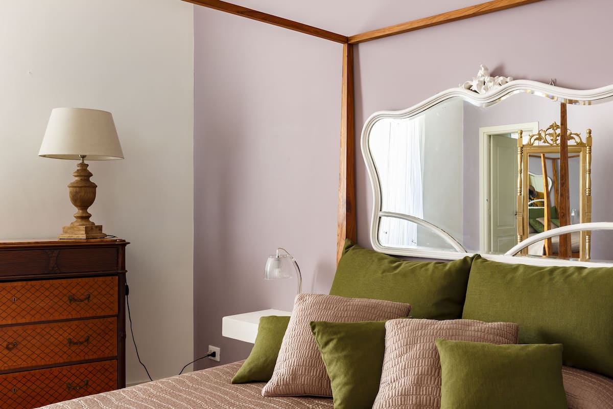 Un dormitorio con cama, cómoda, espejo y lámpara.