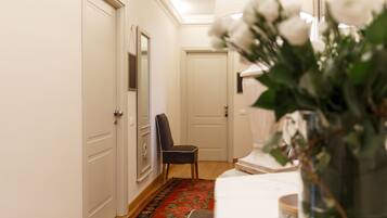 A hallway with a floral rug, a chair, and a vase of flowers.
