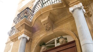 A building facade with classical architecture, featuring columns, a balcony with wrought iron railings, and a large wooden door. - BB 22 Charming Rooms & Apartments (Palermo)