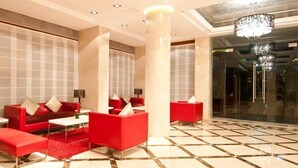 A modern lobby with red seating, a patterned floor, and a chandelier. - The Residency Mumbai (GUNDAVALI, ANDHERI)