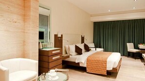 A modern hotel room with a bed, bedside table, chair, and a desk with a chair. - The Residency Mumbai (GUNDAVALI, ANDHERI)