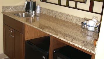 Una cocina compacta con encimera de granito, pileta de acero inoxidable y microondas.