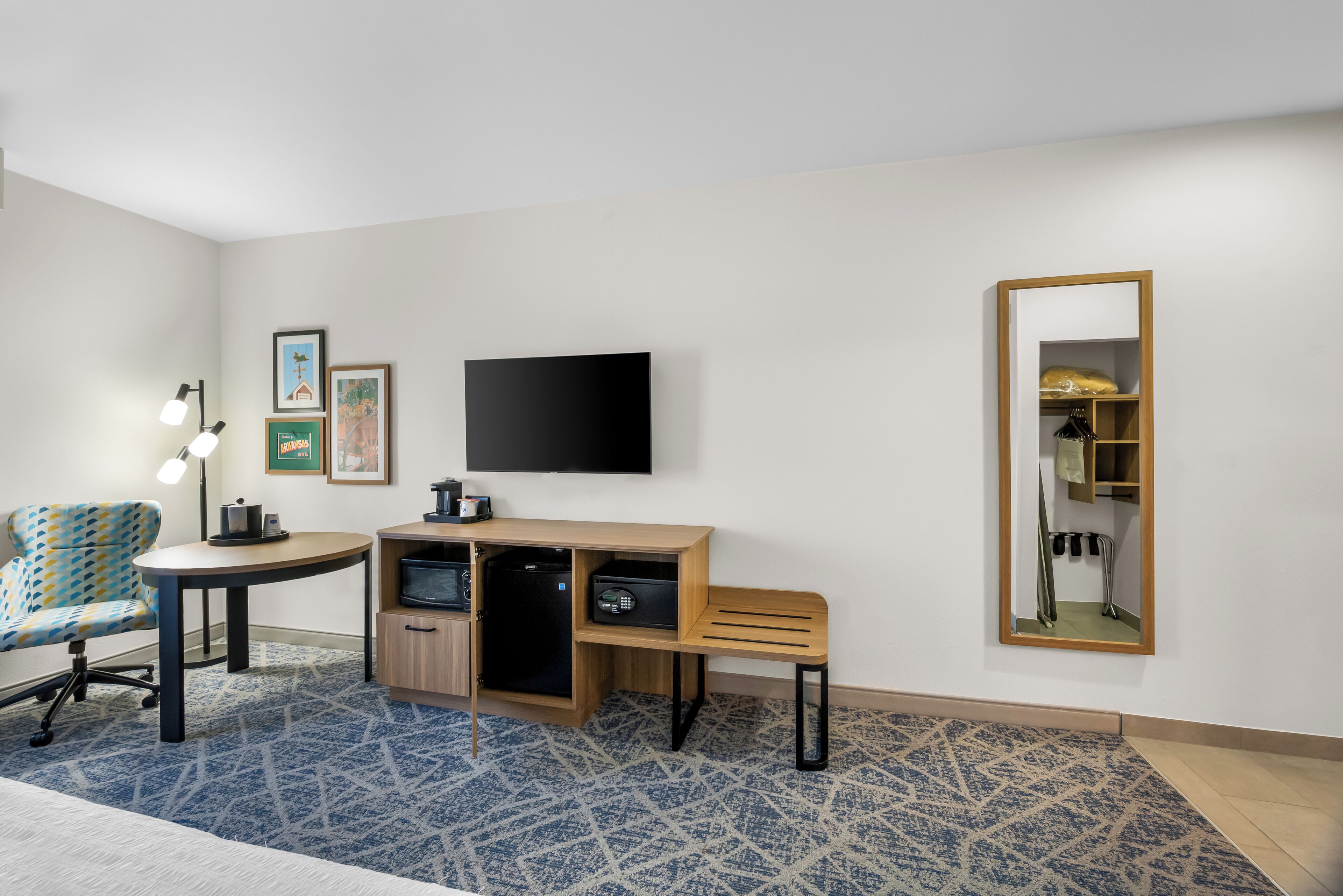 Ein Hotelzimmer mit Schreibtisch, Stuhl, Fernseher und Spiegel.