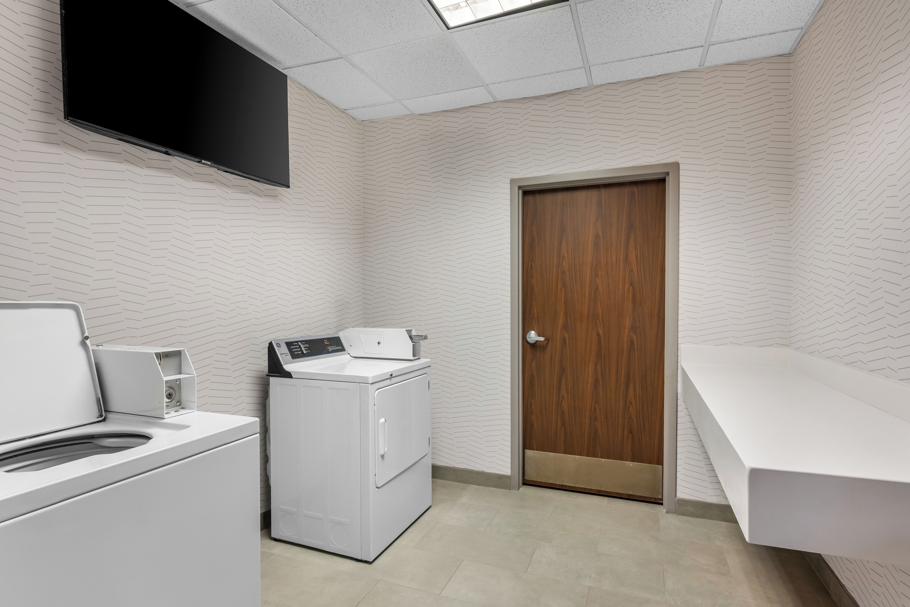 A laundry room with a washing machine, dryer, and a wooden door.