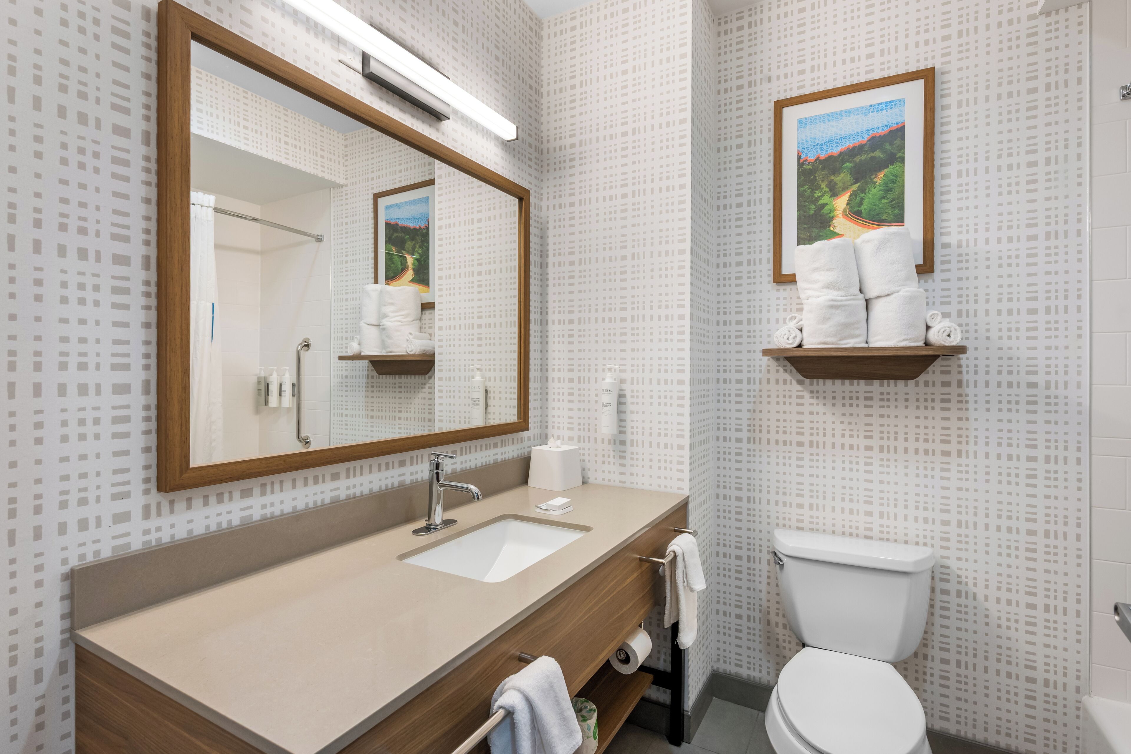 Un baño con lavamanos, espejo, inodoro y un perchero para toallas.