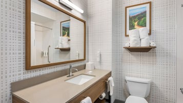 Un baño con lavamanos, espejo, inodoro y un perchero para toallas.