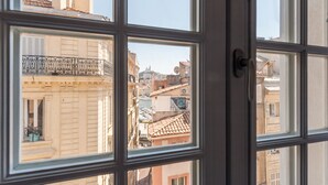 Uitzicht door een ruit met meerdere delen, waarop een stadsgezicht met gebouwen en balkons te zien is.