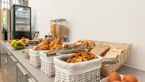 Een ontbijtbuffet met diverse producten, zoals brood, gebak en fruit.