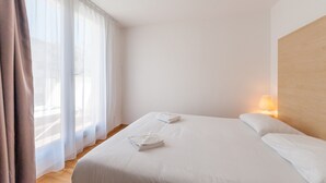 Een hotelkamer met een groot bed, twee kussens en een bedlampje.