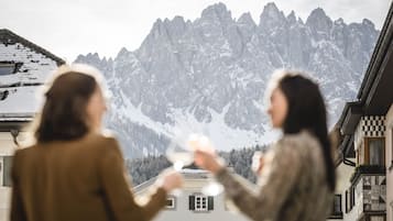 Two people toasting with wine glasses in front of a mountain backdrop.