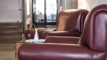 Eine moderne Hotelhalle mit Ledersesseln, einer Vase mit einer einzelnen Blume und einer großen Stehlampe.
