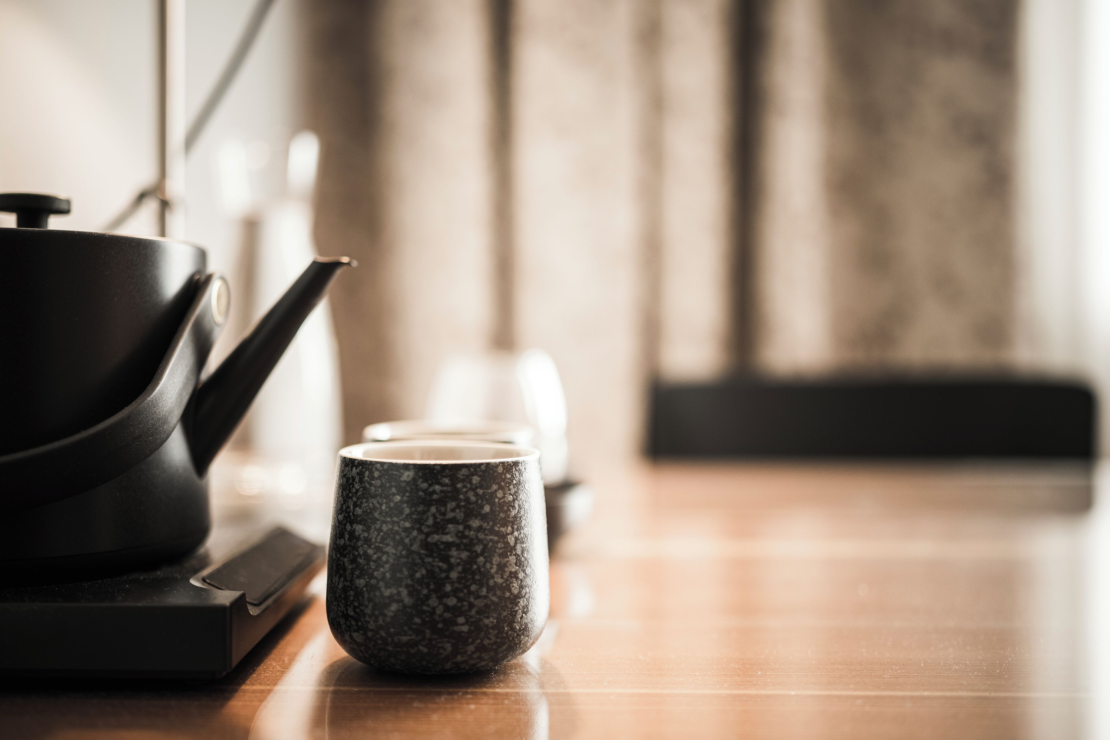 Un coin cuisine avec une théière, une tasse et une bouilloire posés sur un plan de travail en bois.