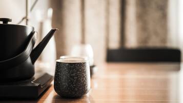 Un coin cuisine avec une théière, une tasse et une bouilloire posés sur un plan de travail en bois.