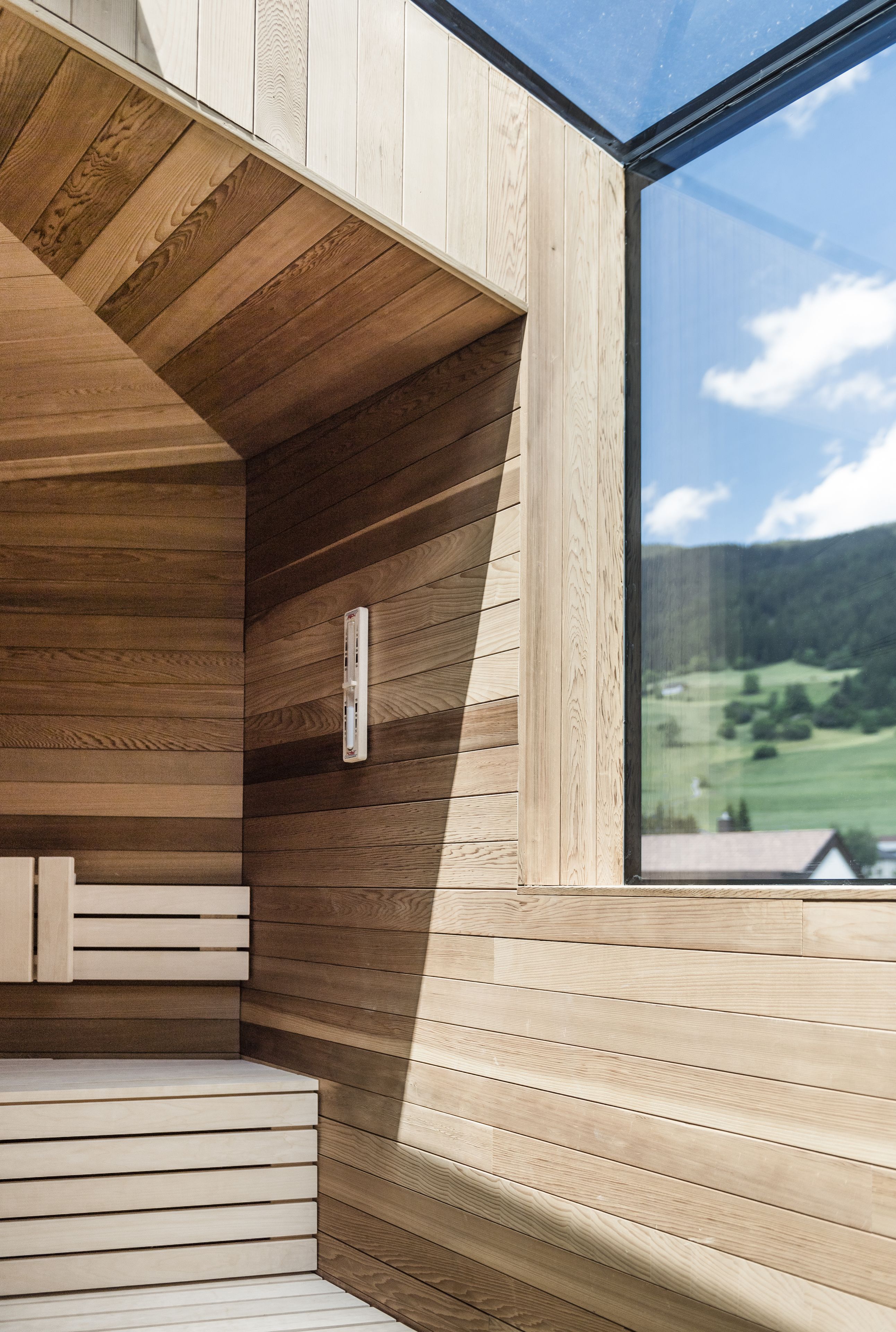 Un interno moderno con pannelli in legno e un'ampia finestra che si affaccia su un paesaggio verde.