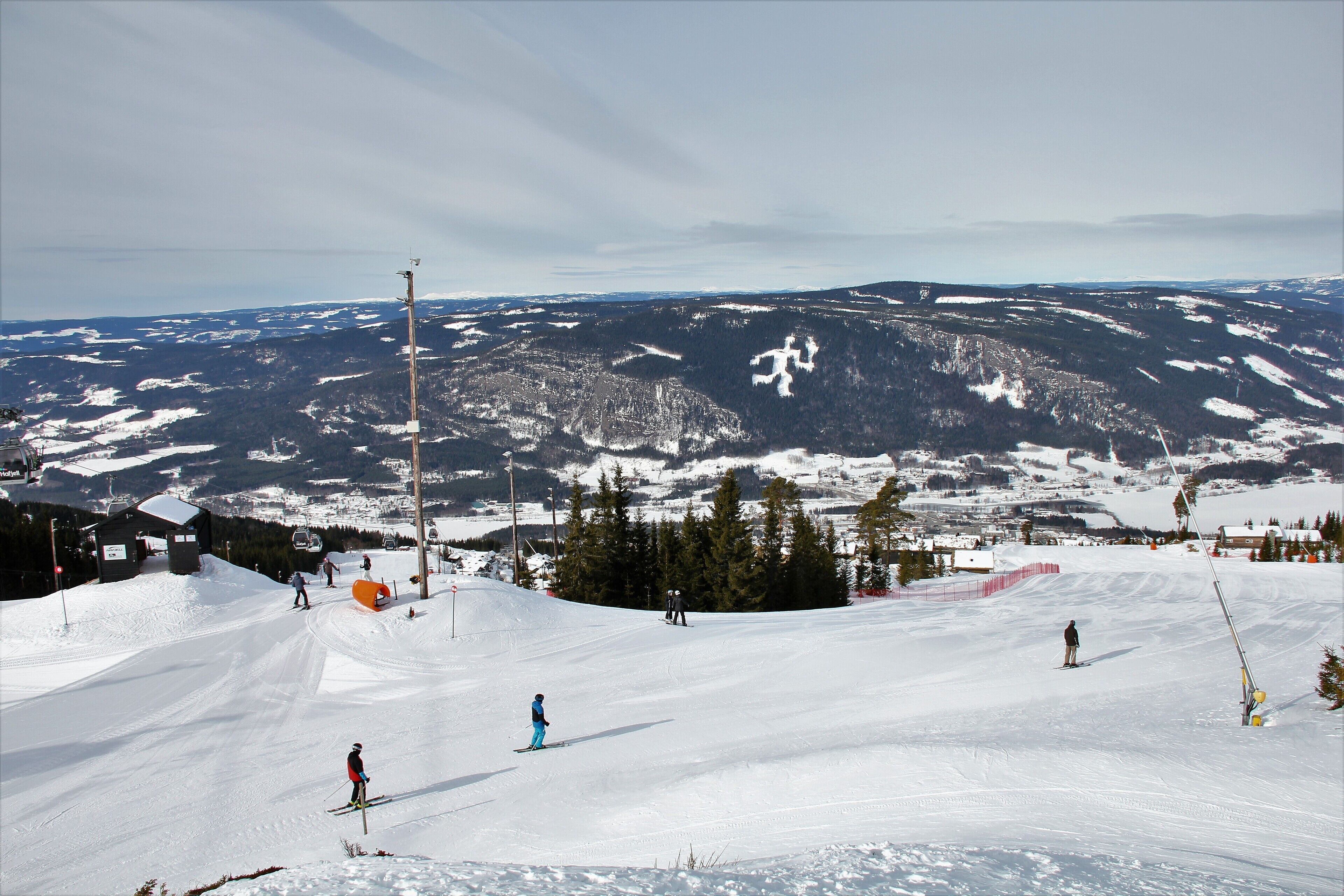 A ski slope with skiers, a chairlift, and a mountain backdrop.