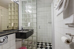 A bathroom with a glass shower enclosure, a black sink, and a white toilet. - Hafjell Hotell (Øyer)