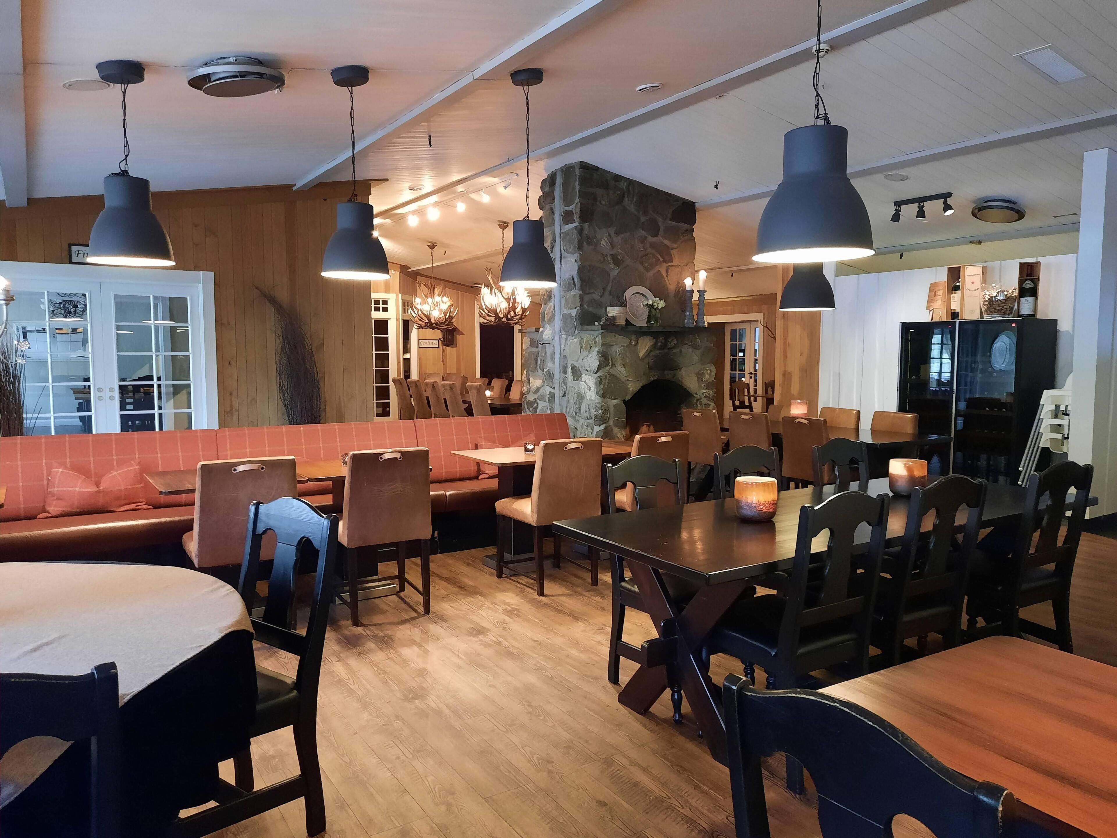 Un restaurante con piso de madera, chimenea de piedra y varias mesas y cabinas.