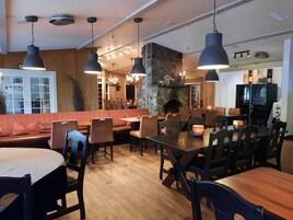Un restaurante con piso de madera, chimenea de piedra y varias mesas y cabinas.