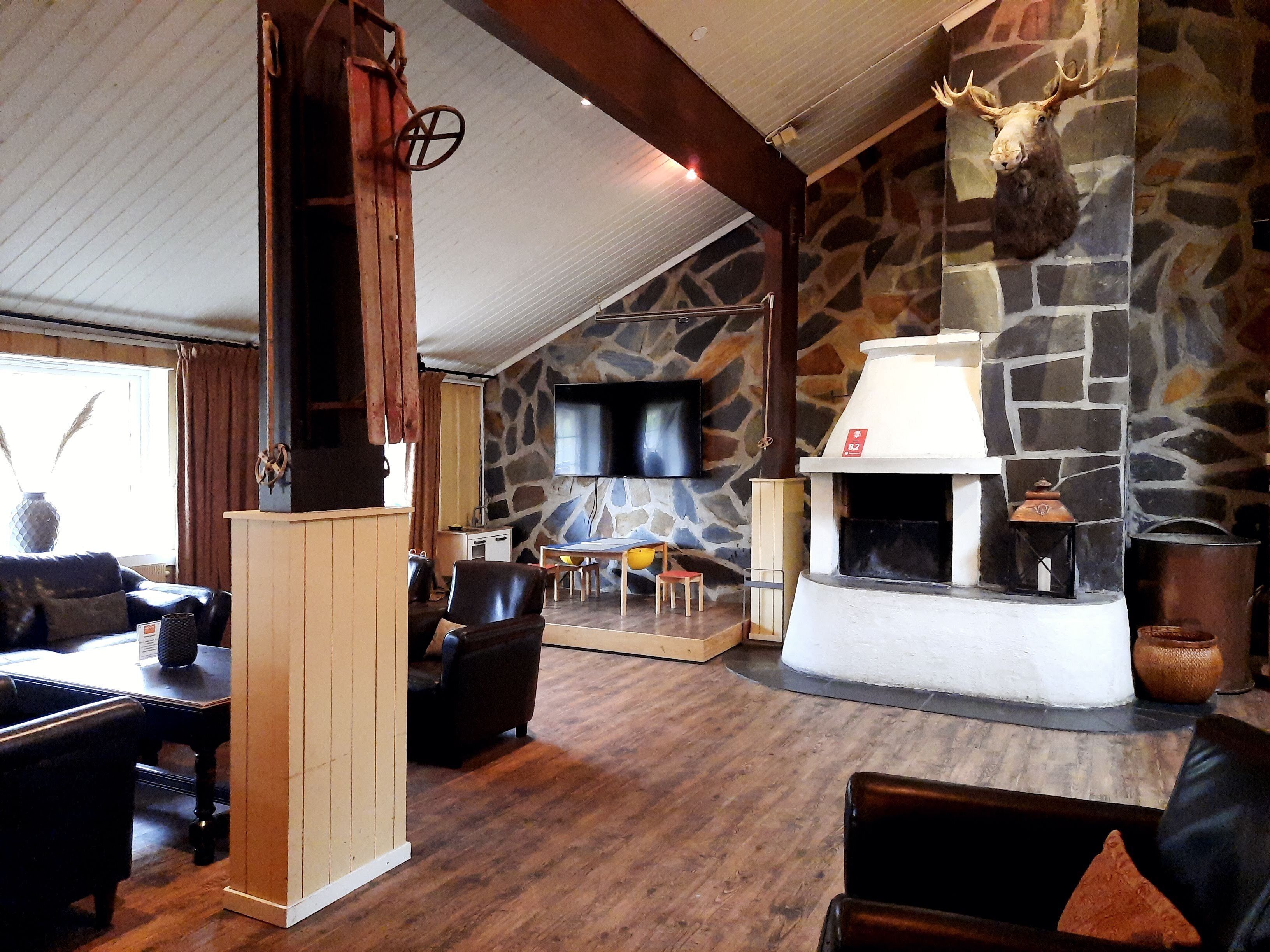 A cozy interior with a stone fireplace, wooden furniture, and a mounted deer head.