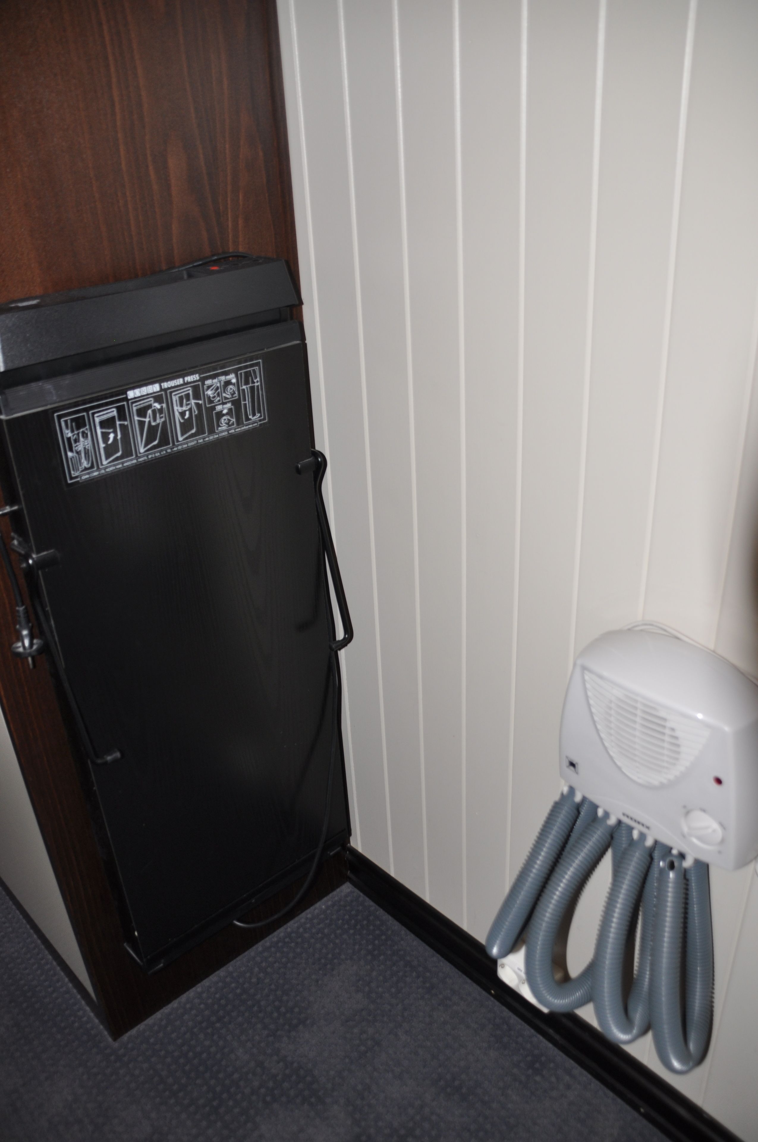 A compact, dark-colored refrigerator with a control panel and a small air conditioning unit beside it.