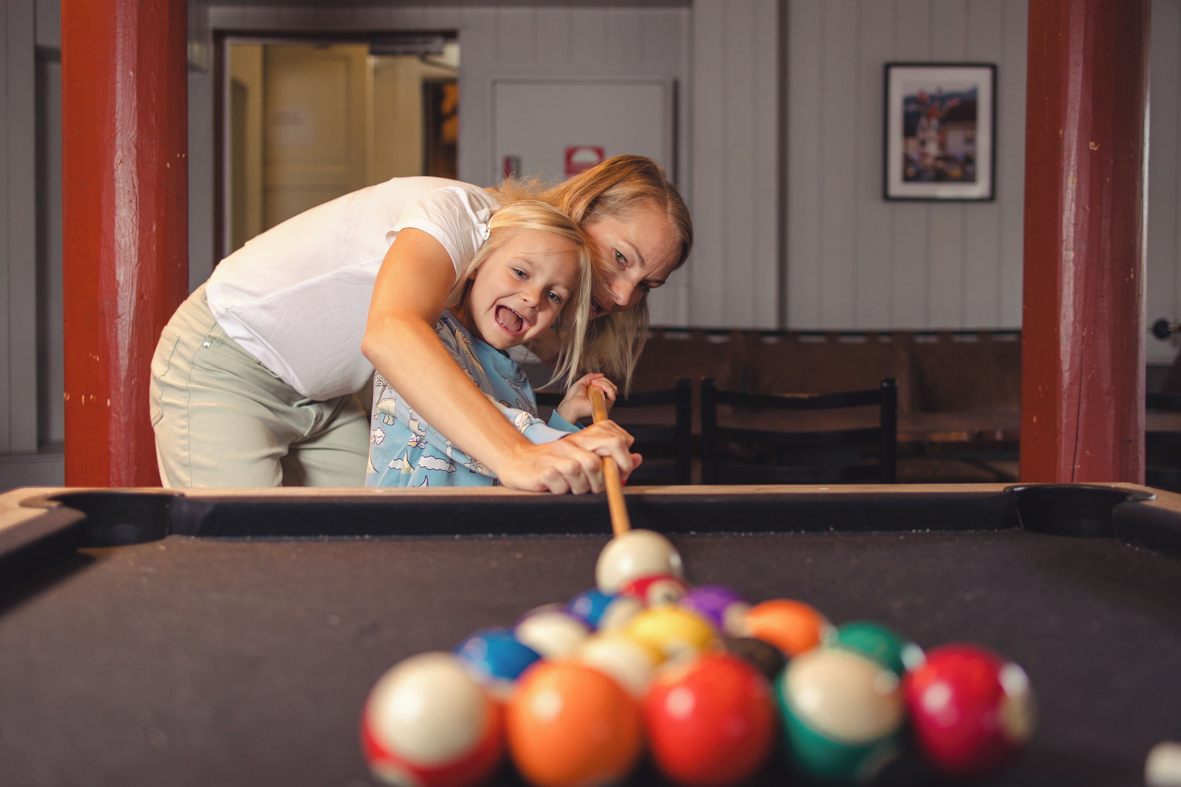 A pool table with balls and a person leaning over it.