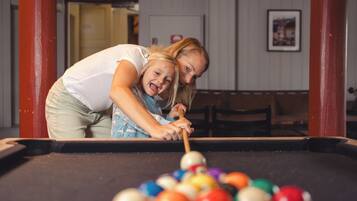A pool table with balls and a person leaning over it.