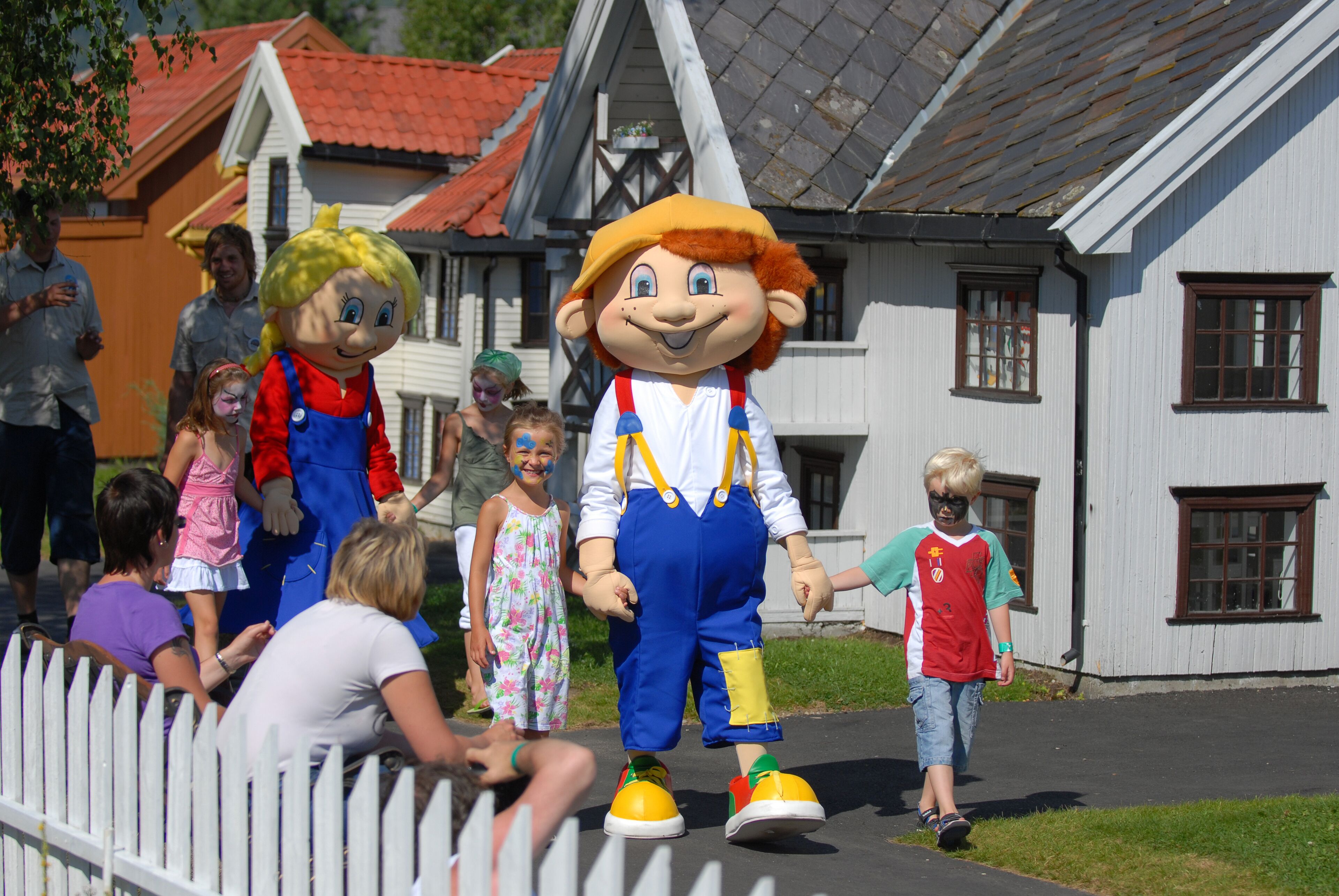 A mascot character in a costume walking on a street.