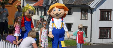 A mascot character in a costume walking on a street.