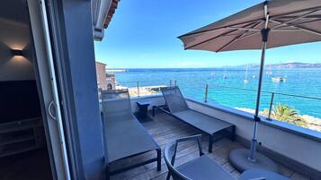 Un balcón con mobiliario exterior, vista al mar y cielo despejado.