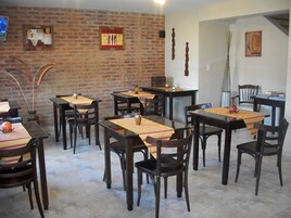 Un comedor con paredes de ladrillo, mesas y sillas de madera.