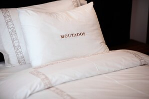 A bed with white bedding and pillows, one of which has the word "MOUTADOS" embroidered on it. - Moutados (Vila Nova de Famalicao)