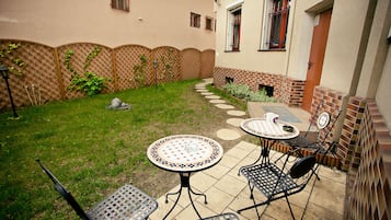 A patio with a round table and four chairs, a brick wall, and a wooden fence.