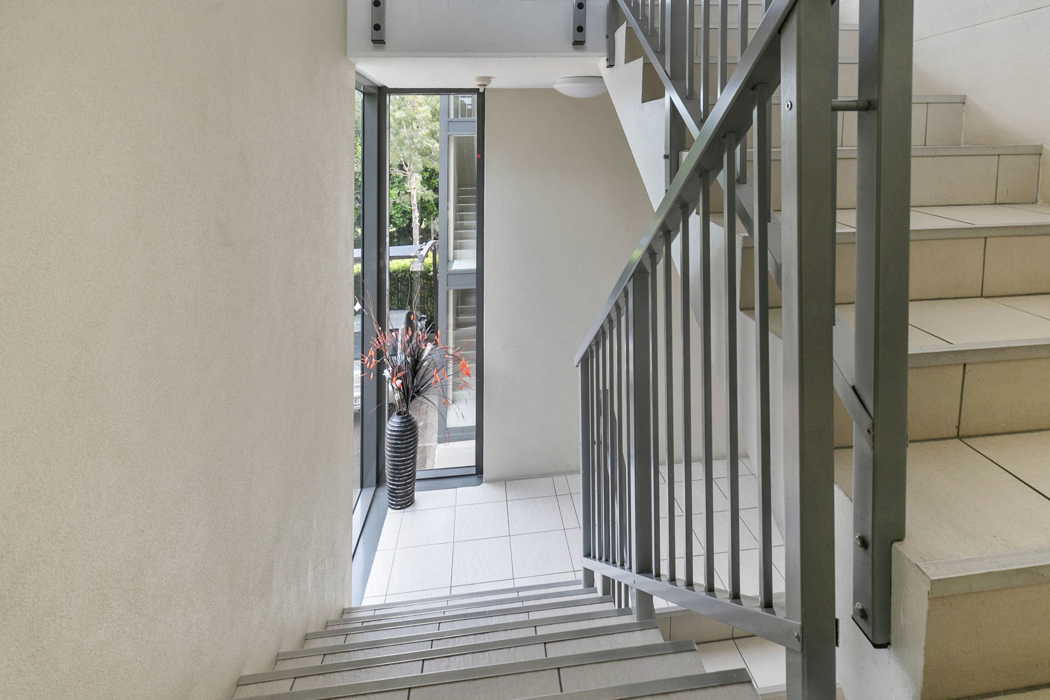 A modern staircase with metal railings leading to a second floor.