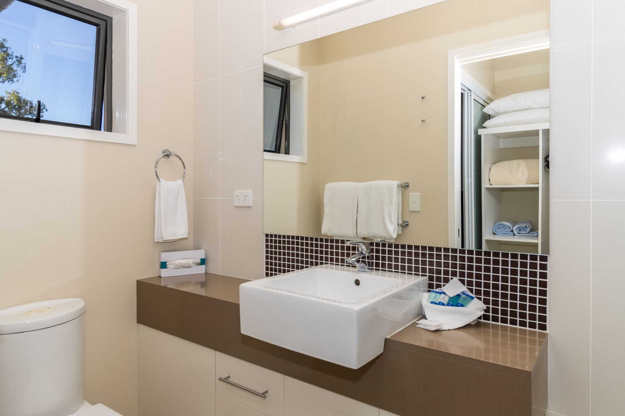 Une salle de bain moderne avec un lavabo blanc, un miroir et un porte-serviettes.