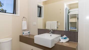 A modern bathroom with a white sink, a mirror, and a towel rack.