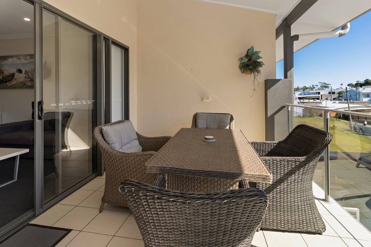A balcony with wicker furniture, a glass door, and a view of the neighborhood.