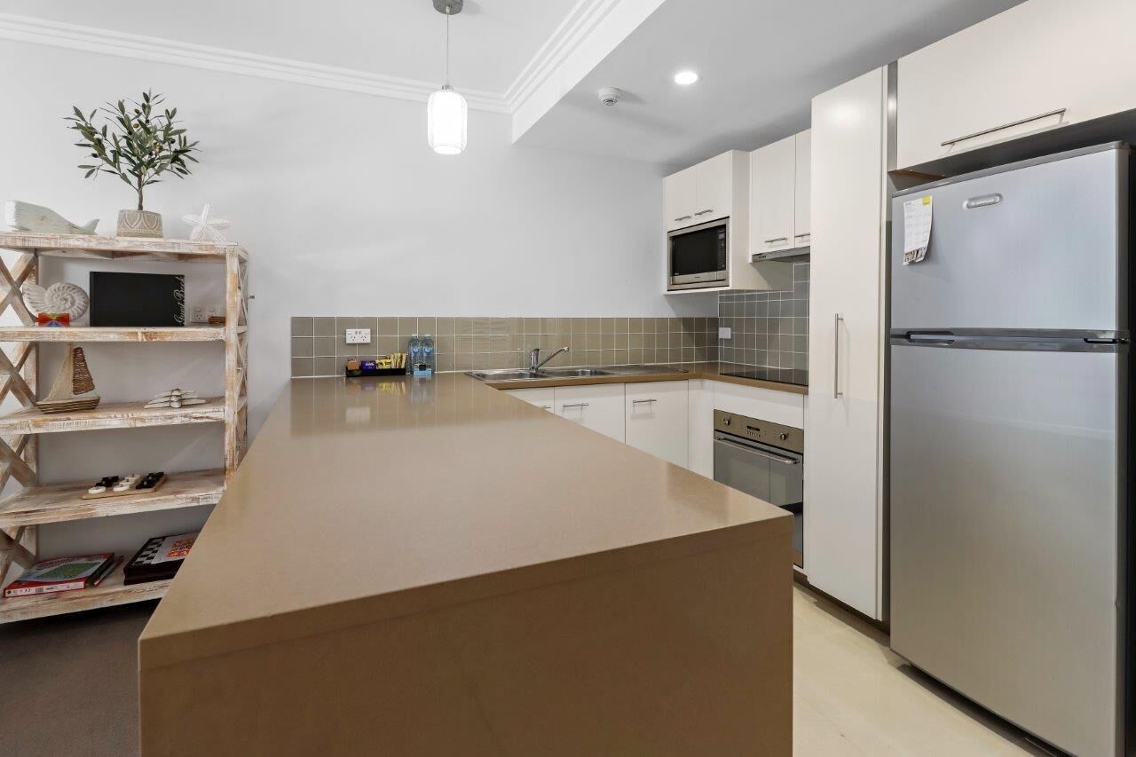 A modern kitchen with a central island, stainless steel appliances, and a white color scheme.