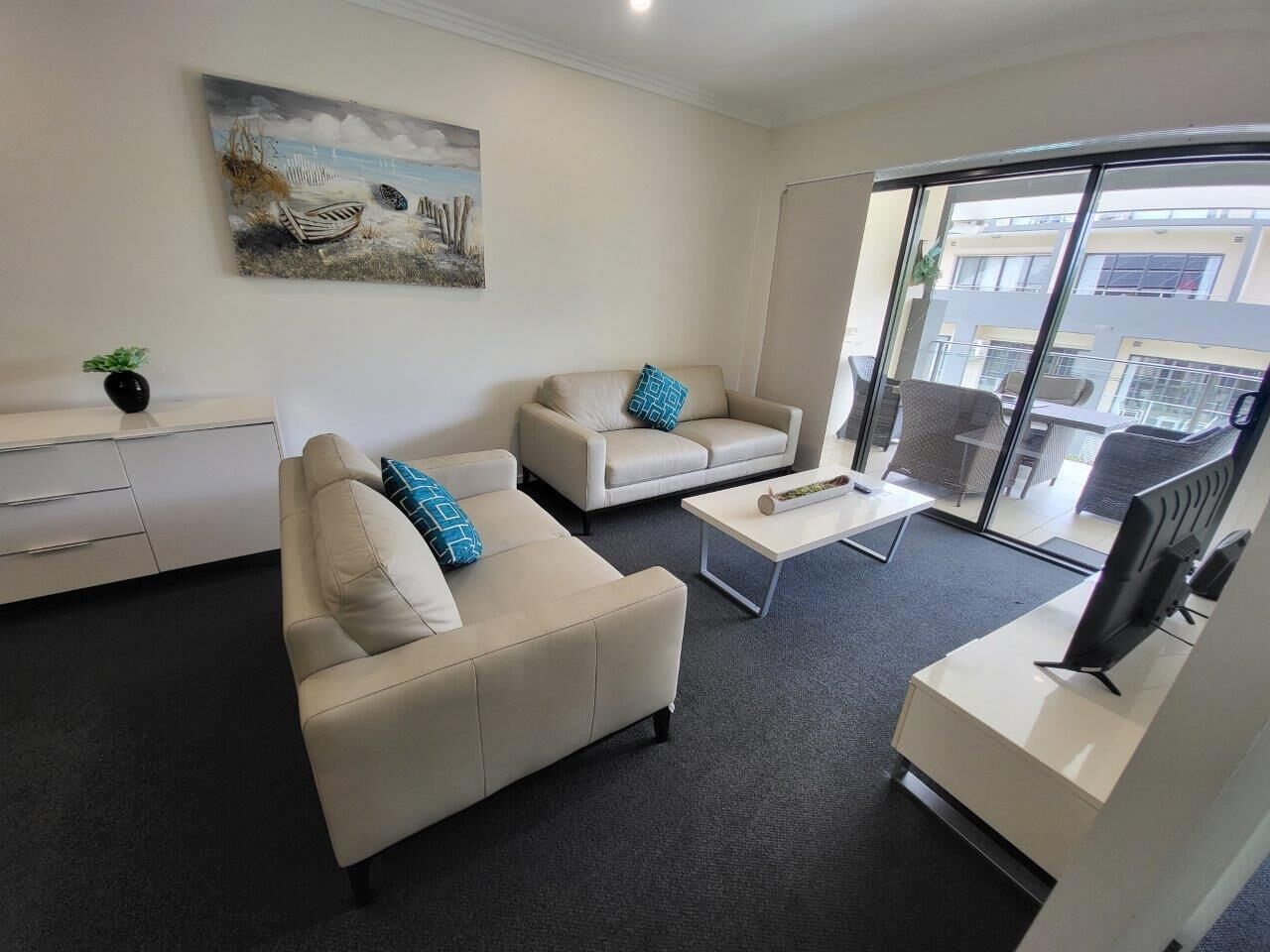 A modern living room with two beige sofas, a coffee table, and a flat-screen TV.