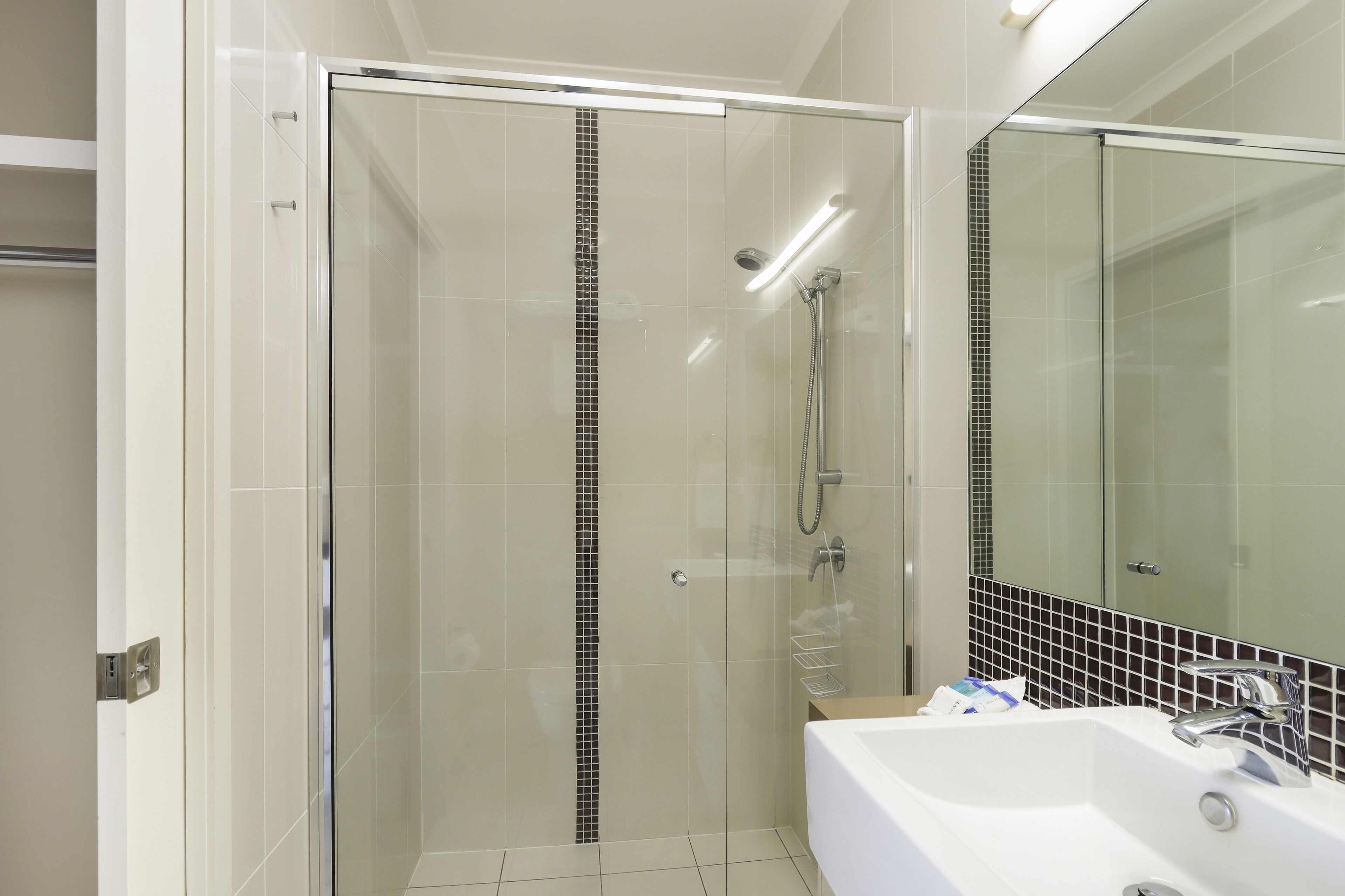 A modern bathroom with a glass-enclosed shower, a white sink, and a tiled backsplash.