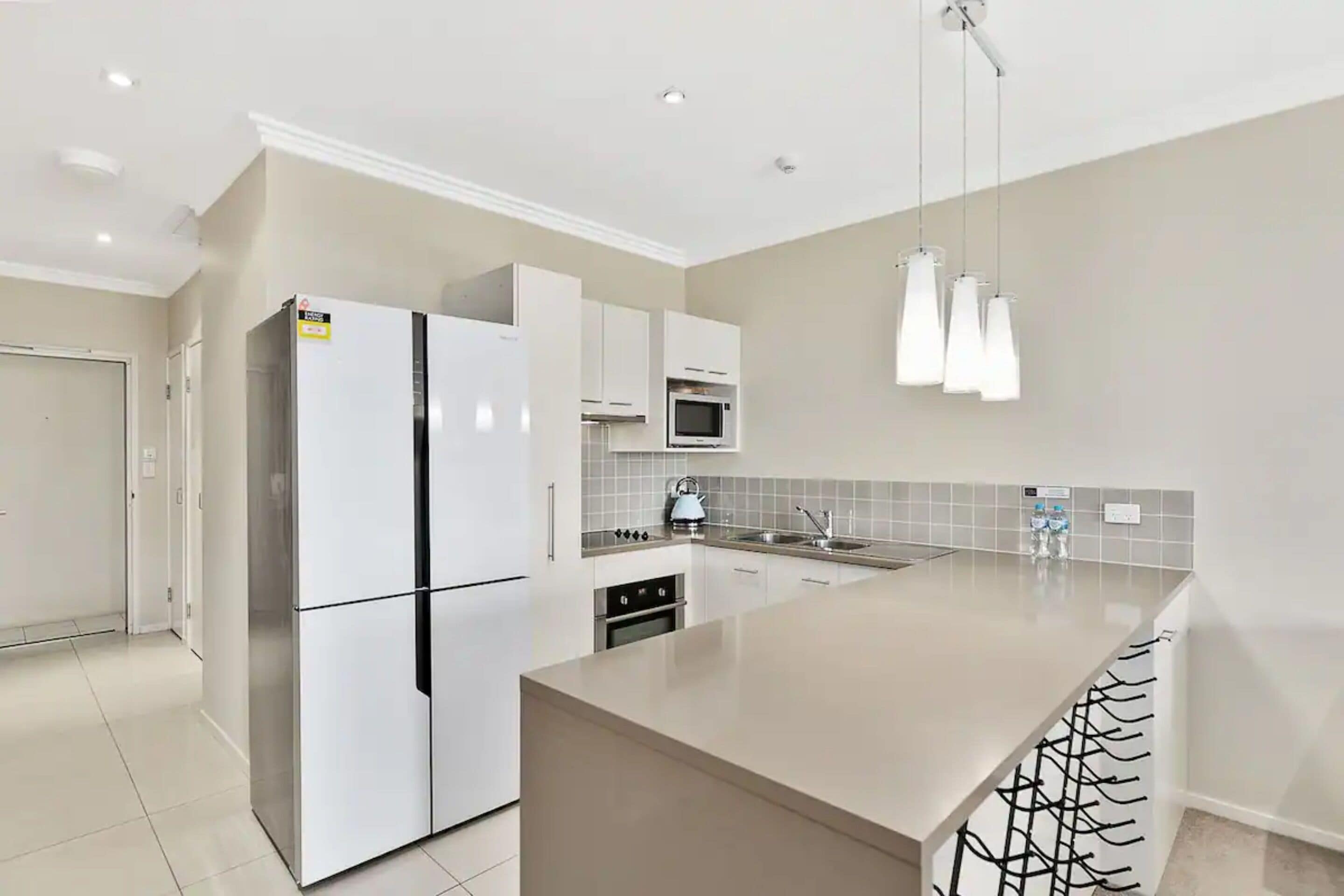 A modern kitchen with a large island, built-in appliances, and pendant lighting.
