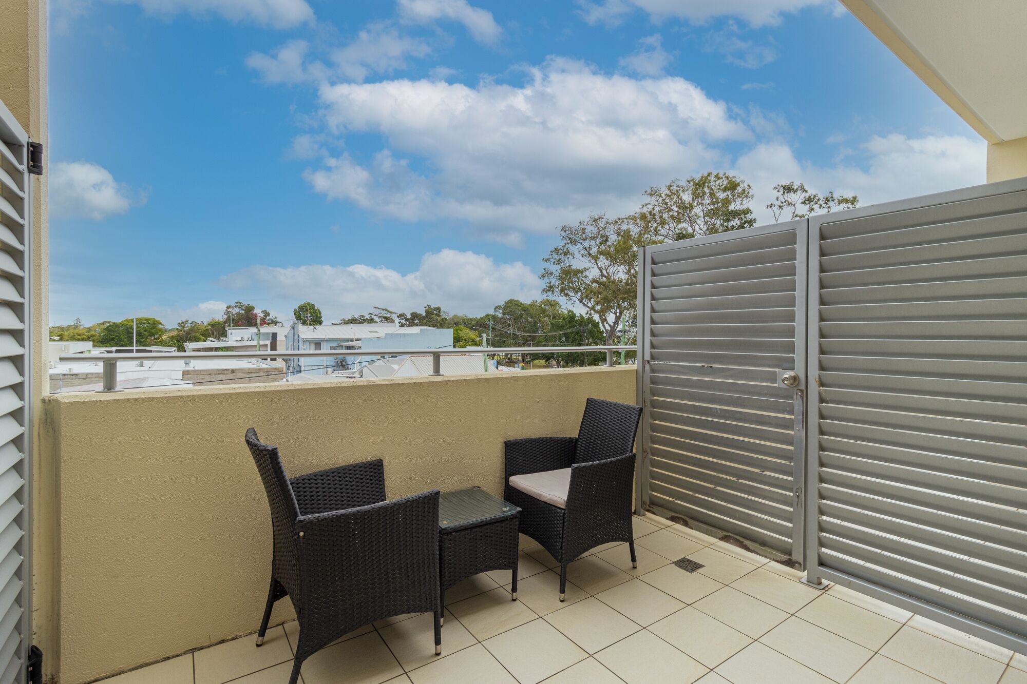 Ein Balkon mit zwei Korbstühlen und einem Metallgitter.
