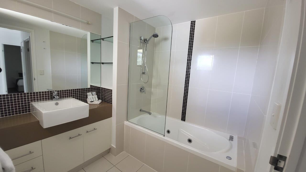 A bathroom with a glass-enclosed shower, a white sink, and a mirror.