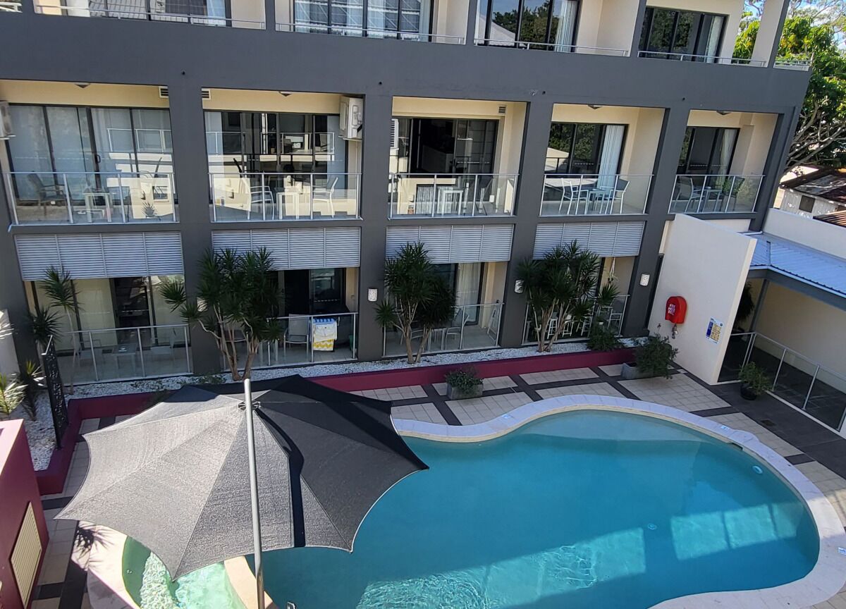 Un edificio moderno con piscina, balcones y zonas de estar al aire libre.